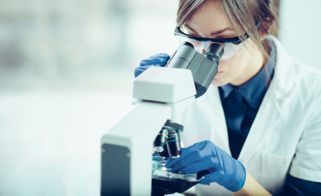 Young scientist looking through a microscope in a laboratory. Yo