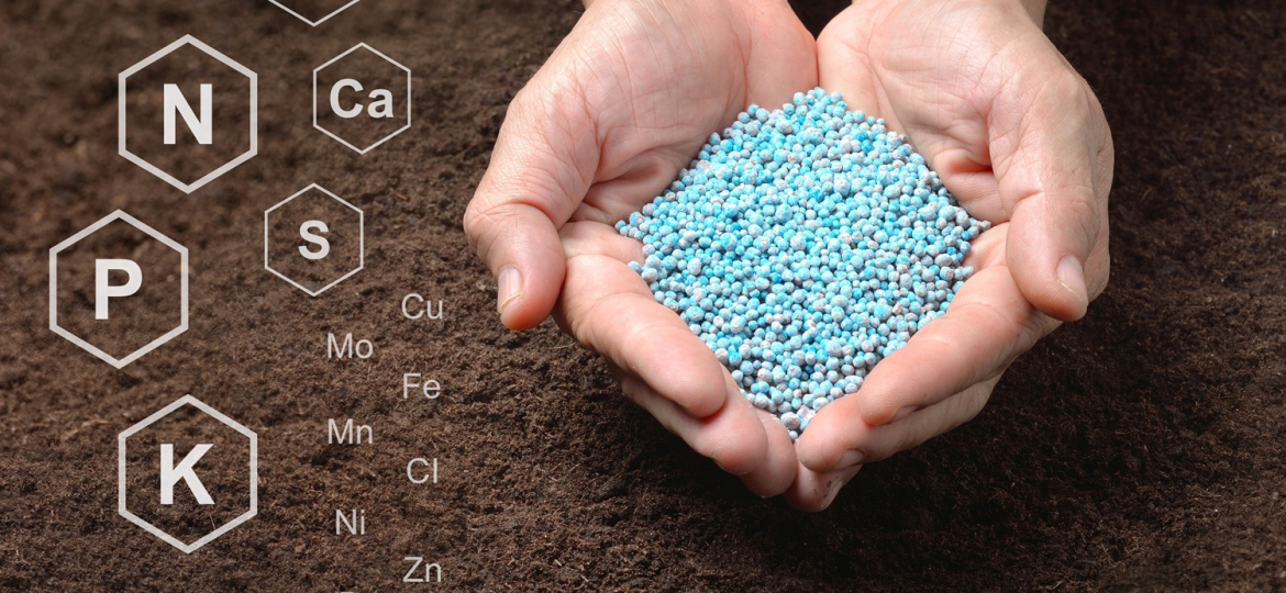 Chemical fertilizers in hand on soil background